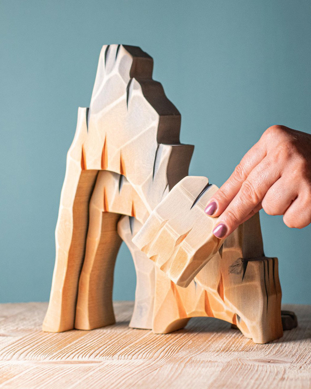 Set of five Bumbu toys wooden mountain cliff pieces, each uniquely carved and painted to look like rugged rock formations. Designed for open-ended and small-world play. Available from Babipur.