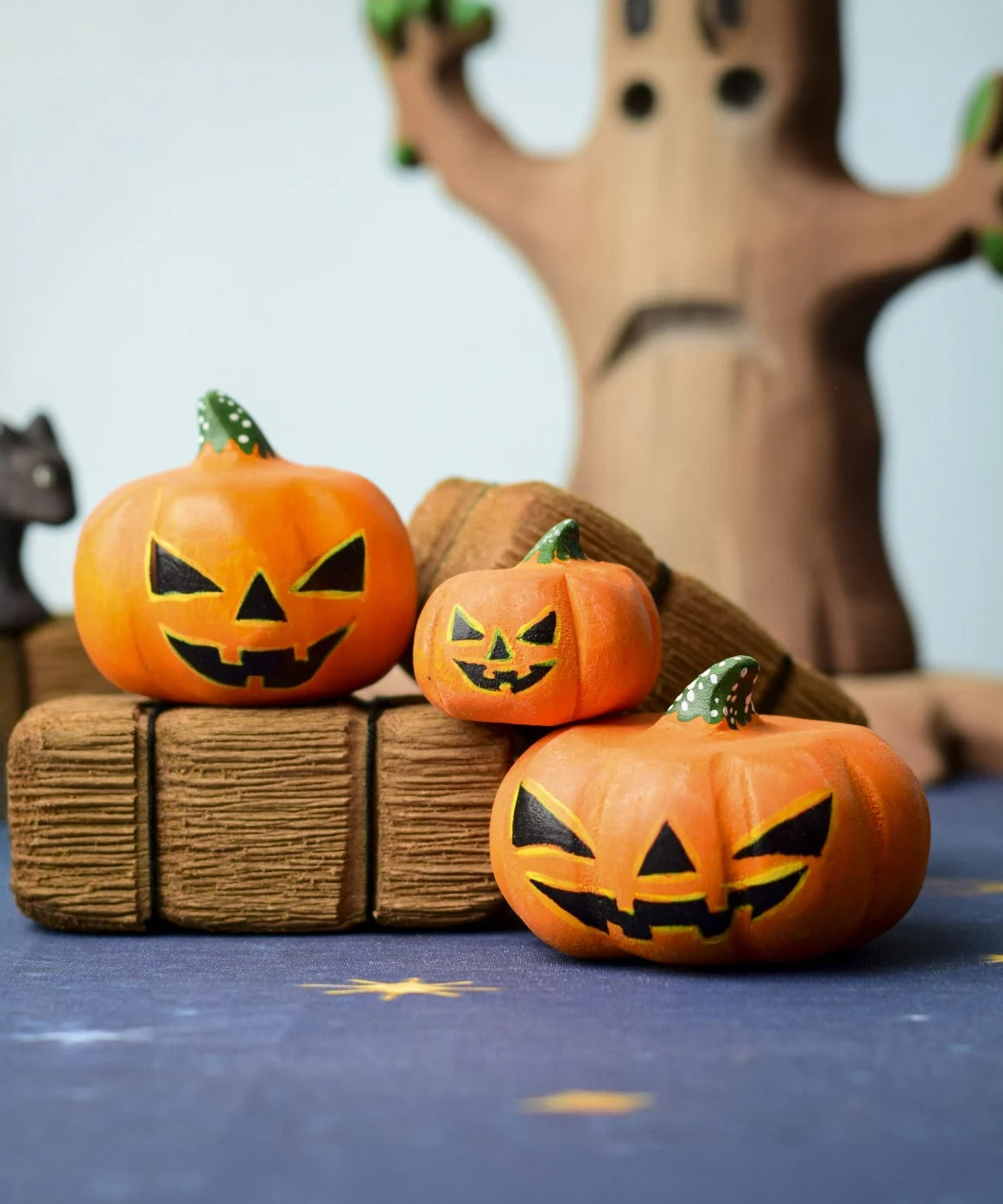 The small, medium and large Bumbu Toys Halloween Pumpkins are sat on Bumbu hay-bales, with the Bumbu scardy cat and and Bumbu large spooky tree in the background. Each pumpkin is hand made and hand painted