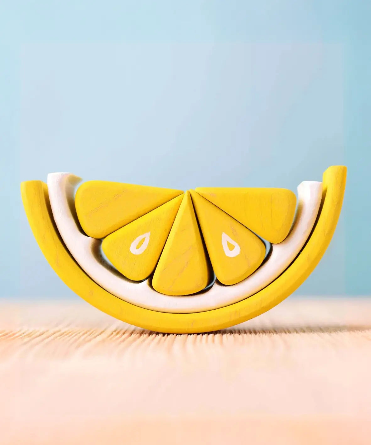 The Bumbu Toys Wooden Lemon toy, showing the bright yellow wedge-shaped pieces.