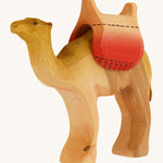 Bumbu wooden camel figure with saddle on a plain background.