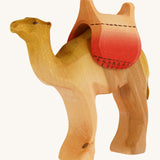 Bumbu wooden camel figure with saddle on a plain background.