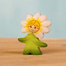 Bumbu handcrafted wooden daisy flower child figure with hand painted facial features standing on a wooden surface
