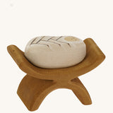 Bumbu wooden baby Jesus figure in a crib on a plain background.