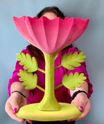 A person holding up the Bumbu Wooden Large Pink Flower in front of them.