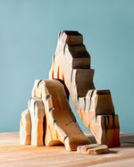 Bumbu Mountain Cliffs wooden toy set, featuring five handcrafted cliff pieces in natural earthy tones. The carved shapes stack and arrange to create a rocky mountain landscape for imaginative small-world play. Sold by Babipur.