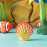 Bumbu handmade and hand painted orange and red wooden seashell figure  with a clownfish and reef set in the background