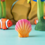 Bumbu handmade and hand painted orange and pink wooden seashell figure  with a clownfish and reef set in the background