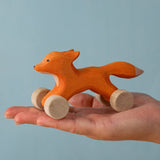 An adult hand holding the Bumbu handmade and hand painted rolling fox available at Babipur showing size