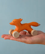 An adult hand holding the Bumbu handmade and hand painted rolling fox available at Babipur showing size