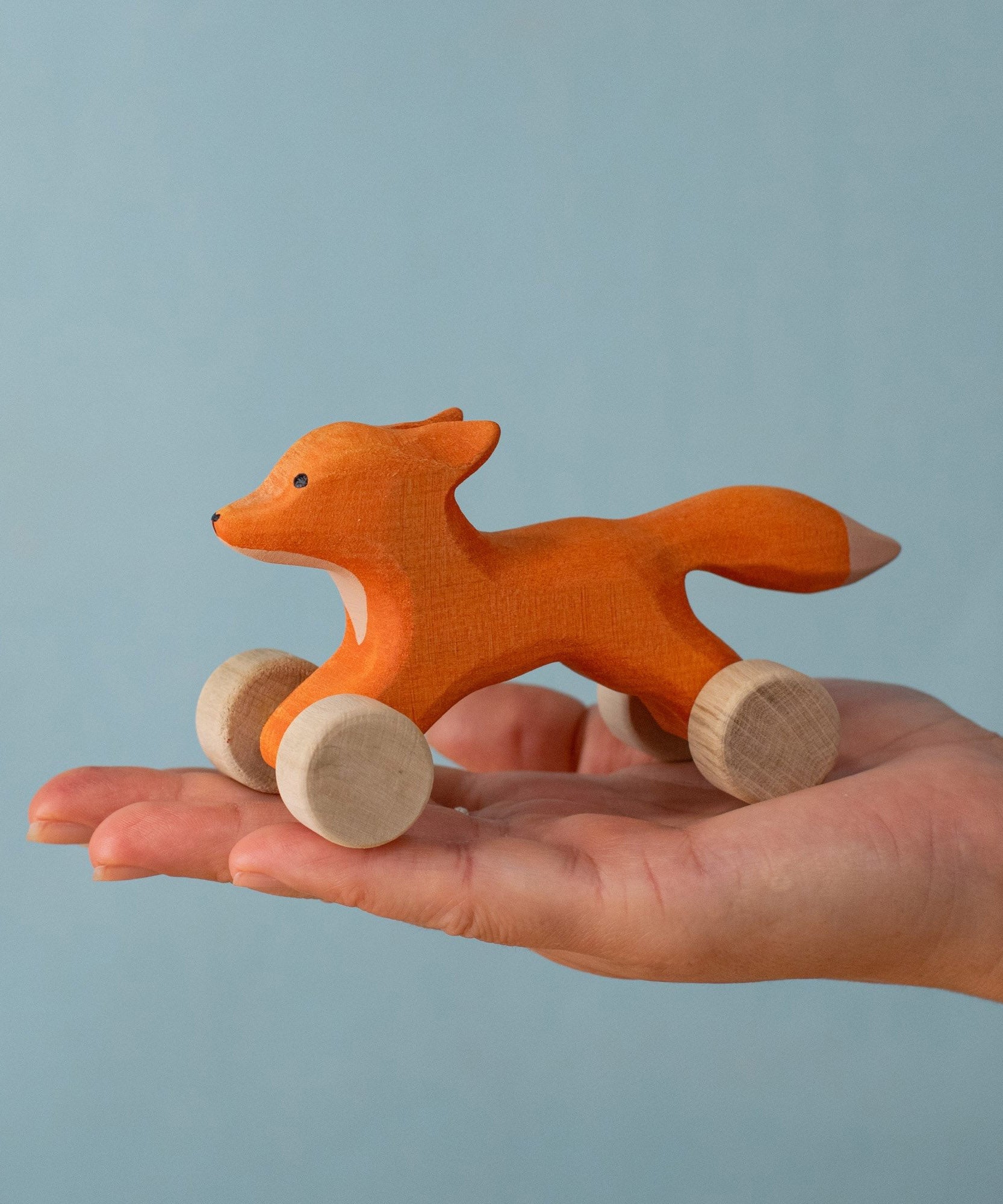 An adult hand holding the Bumbu handmade and hand painted rolling fox available at Babipur showing size