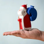 A person holding the Bumbu Santa in their hand. The image also shows the natural wood grain of the piece