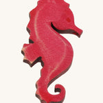 Bumbu pink wooden seahorse figure on a plain background.
