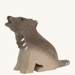 A Bumbu small wooden sitting wolf cub on a plain background.