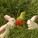 Bumbu handcrafted wooden strawberry plant on grass with white rabbits standing near