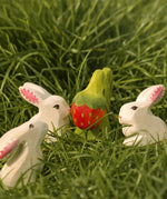 Bumbu handcrafted wooden strawberry plant on grass with white rabbits standing near
