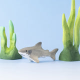 Bumbu handmade and hand painted wooden grey baby shark figure surrounded by the Bumbu green coral figures