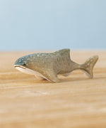 Bumbu handmade and hand painted wooden grey baby whale shark figure available at Babipur and resting on a wooden surface