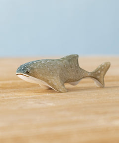 Bumbu handmade and hand painted wooden grey baby whale shark figure available at Babipur and resting on a wooden surface