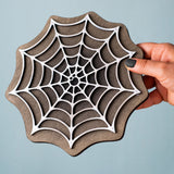 A hand holding the Bumbu handmade and hand painted white cobweb piece showing size