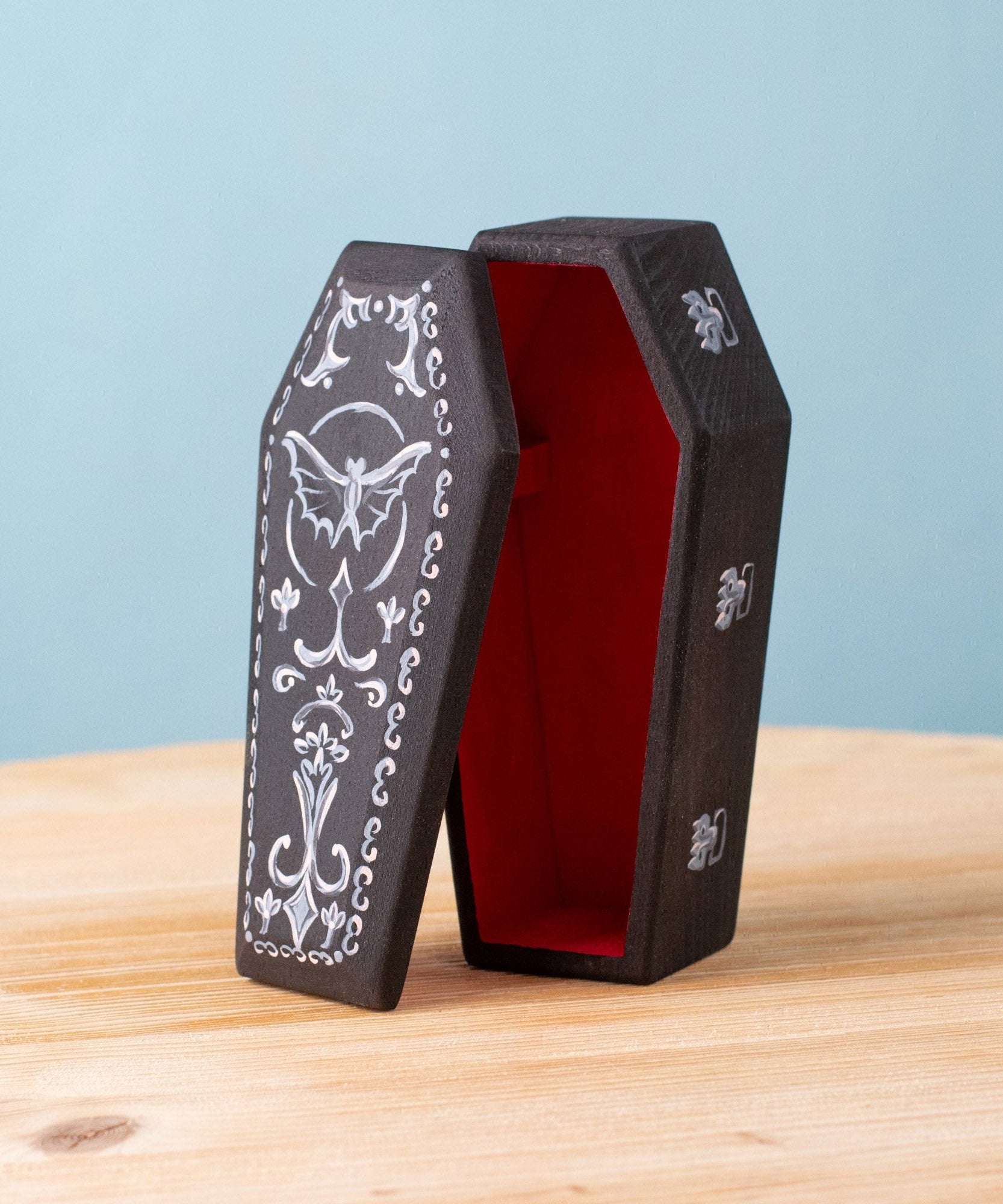 Bumbu handmade and hand painted wooden black coffin with white detail and red inside available at Babipur.