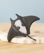 A close up of the  Bumbu handmade and hand painted wooden black manta ray figure showing the underside detail
