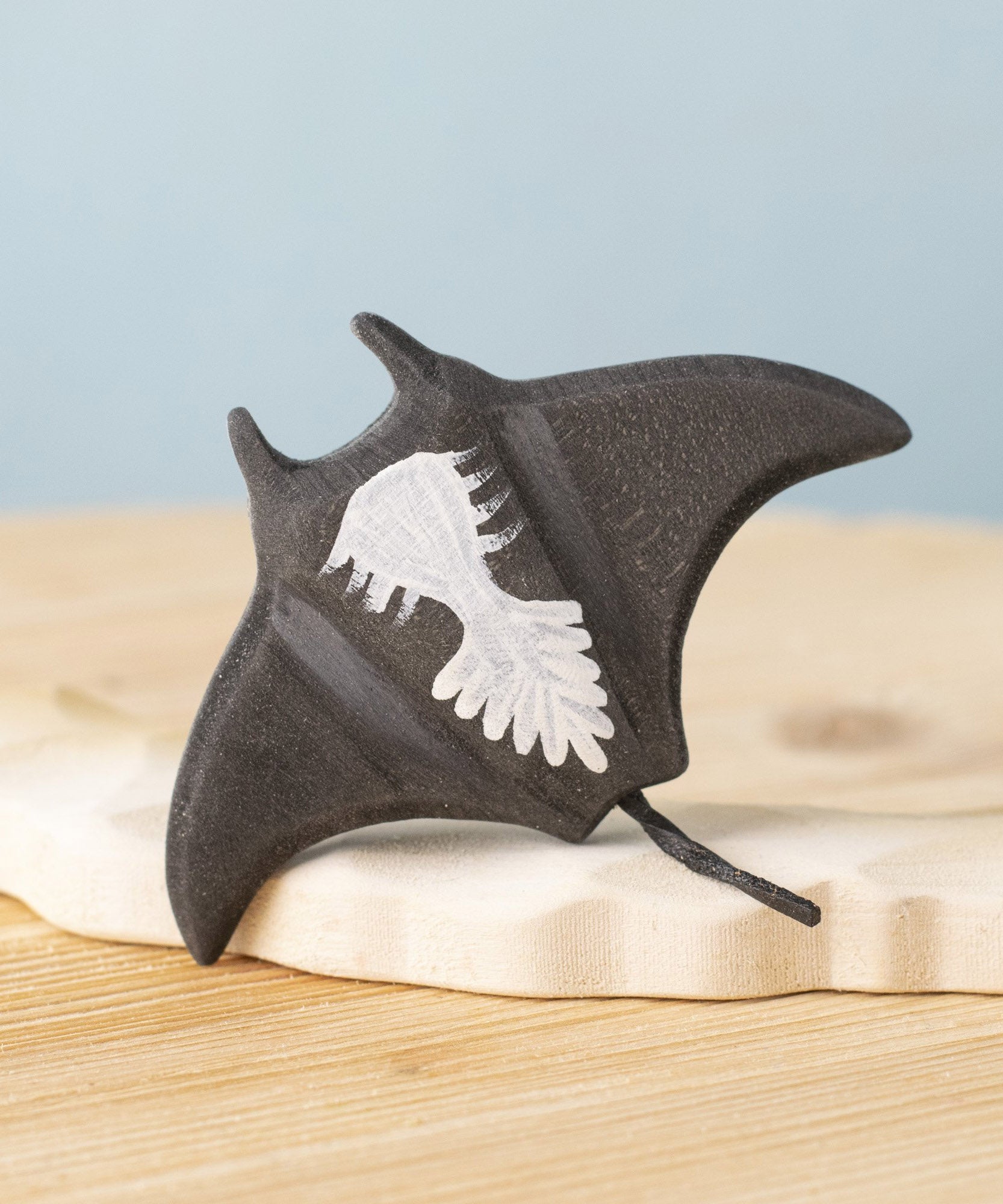 A close up of the  Bumbu handmade and hand painted wooden black manta ray figure showing the underside detail