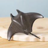 Bumbu handmade and hand painted wooden black manta ray figure available at Babipur and resting on a sandy island