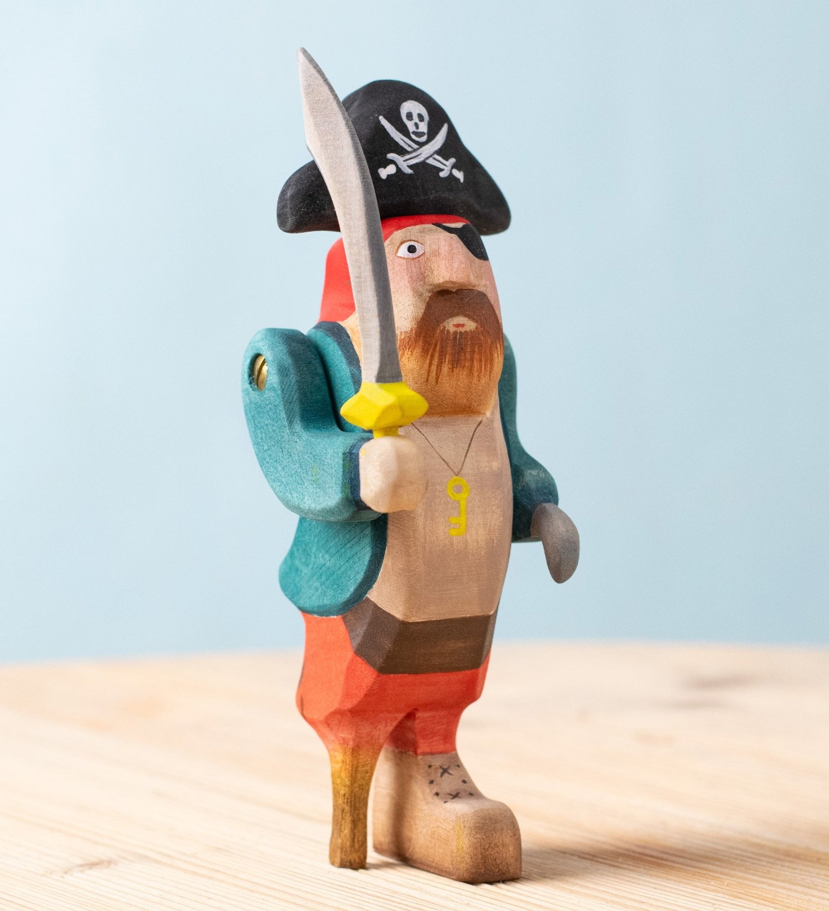 Bumbu handmade and hand painted pirate wooden figure available at Babipur. Wearing a blue coat, red trousers and a black hat. Features a sword and a wooden leg