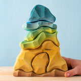 An adult hand holding the bottom of the Bumbu handmade and hand painted wooden reef set showing size