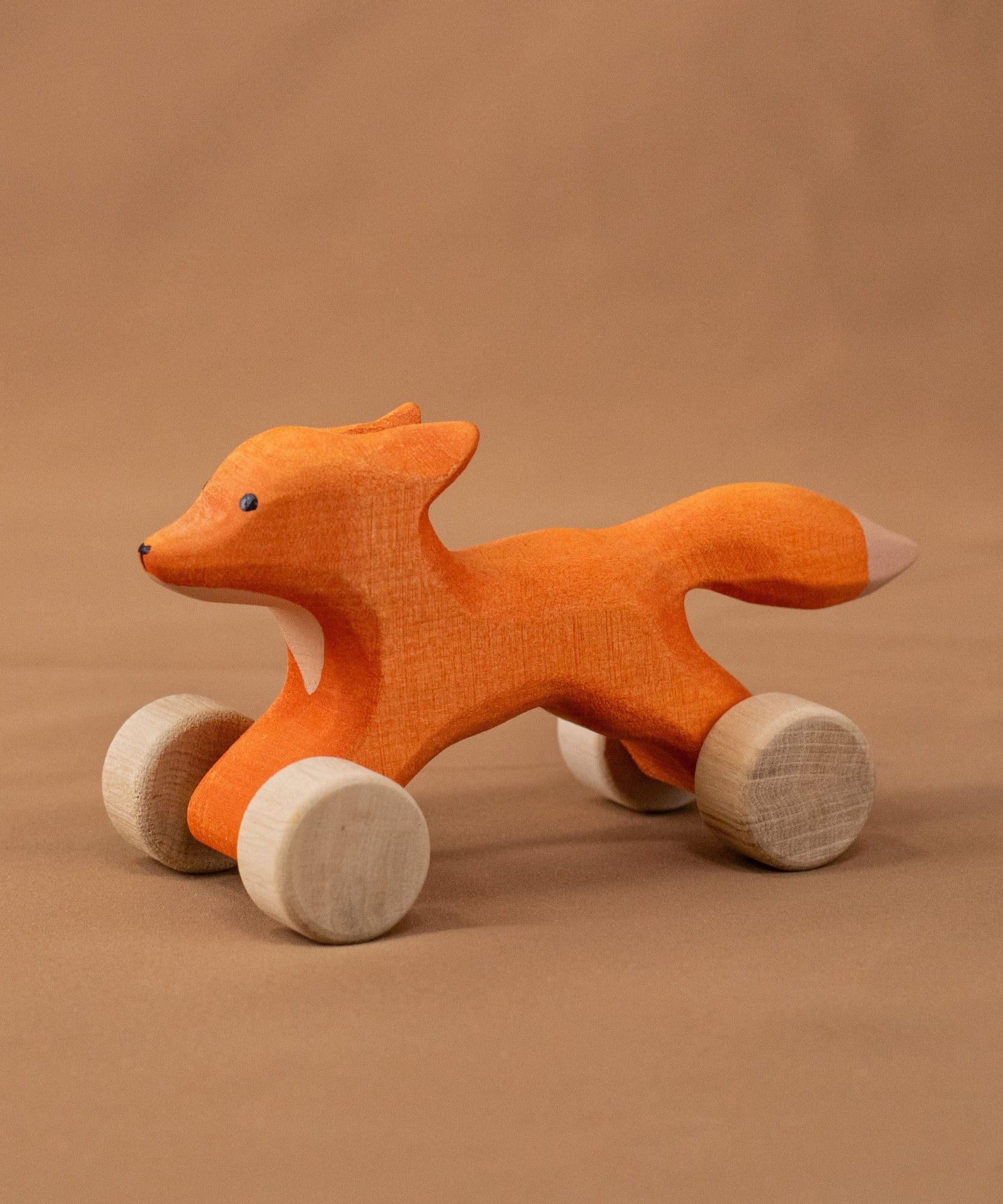 Bumbu handmade and hand painted rolling fox standing on a soft brown cloth