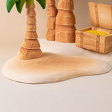 Bumbu handmade and hand painted wooden sandy island piece with a palm tree and treasure chest on top making a beach playscene