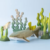 Bumbu handmade and hand painted wooden grey whale shark figure next to a swimming baby whale sark surrounded by Bumbu coral reef pieces available at Babipur.