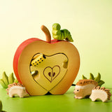 Bumbu handcrafted wooden green caterpillar figure standing on a apple puzzle set with a hedgehog family figures in front