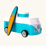 The Candylab VW Beach bus in blue, with a wooden blue and yellow surf board propped up next to the van, The image is on a cream background