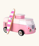 The Candylab VW Beach bus in pink, with a wooden pink and white stripe surf board propped up next to the van, The image is on a cream background