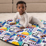 A child happily sat on the Etta Loves x Camille Walala Reversible Playmat, exploring the colourful shape print