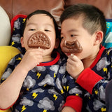The Cocoa Loco Halloween lollies being held by two playful boys sitting on a sofa. This is a funny picture, they're posing with the lollies over their mouths.