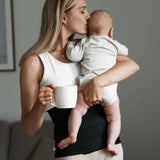 A person enjoying cuddle time with a baby, wearing the Lola & Lykke Core Restore Postpartum Belly Band