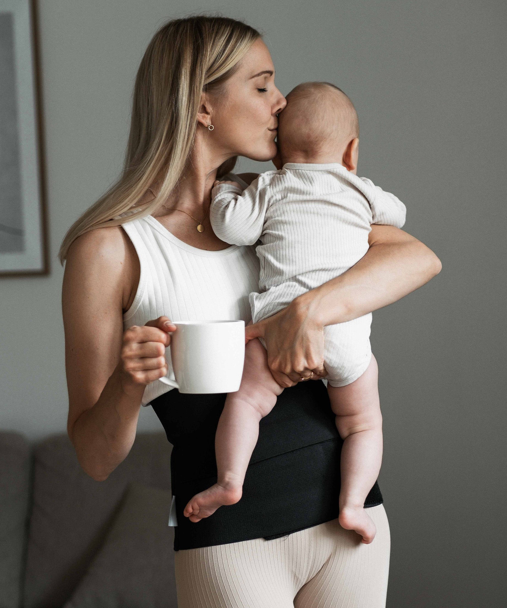 A person enjoying cuddle time with a baby, wearing the Lola & Lykke Core Restore Postpartum Belly Band