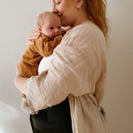 A person cuddling a baby, wearing the Lola & Lykke Core Restore Postpartum Belly Band