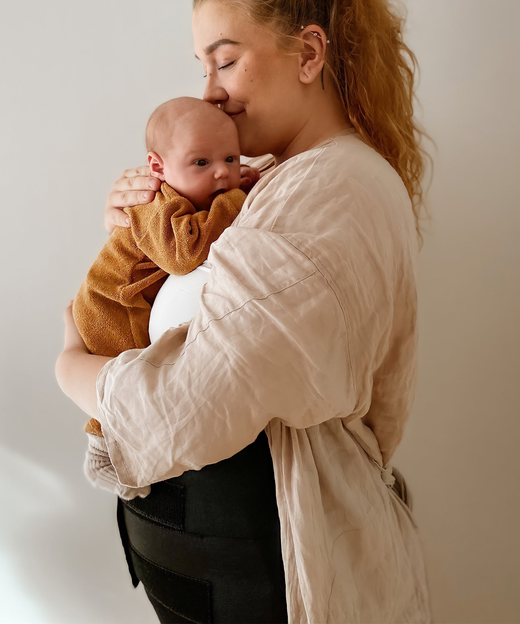 A person cuddling a baby, wearing the Lola & Lykke Core Restore Postpartum Belly Band