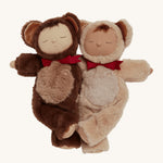 Olli Ella Cozy Dinkum Dolls Teddy Twiggy and Teddy Crumble together on a cream background. On the left is Teddy Twiggy wearing a soft, fluffy, brown outfit with a hood and teddy ears, and a red bow tie. On the right is Teddy Crumbles with a soft, fluffy, sand coloured outfit with a hood, teddy ears and a red bow tie.