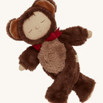 Olli Ella Cozy Dinkums - Teddy Twiggy with its arms wide open and its legs crossed, showing how the arms and legs of the doll can move with ease, on a cream background. Teddy Twiggy has a warm, smiling, sleeping face, a cute button nose and a patch of dark brown hear poking out from underneath its hood.