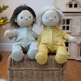 Pair of Olli Ella Dinkum Dolls wearing matching pointelle pyjamas in honey yellow and sage green, available to buy at Babipur.