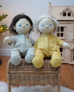 Pair of Olli Ella Dinkum Dolls wearing matching pointelle pyjamas in honey yellow and sage green, available to buy at Babipur.