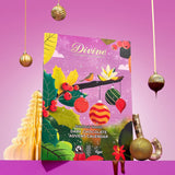 A decorative product shot of a Divine Chocolate themed Advent Calendar, surrounded by festive props including hanging gold ornaments, a gold Christmas tree, chocolate drizzle, and wrapped chocolates on a solid pink background.