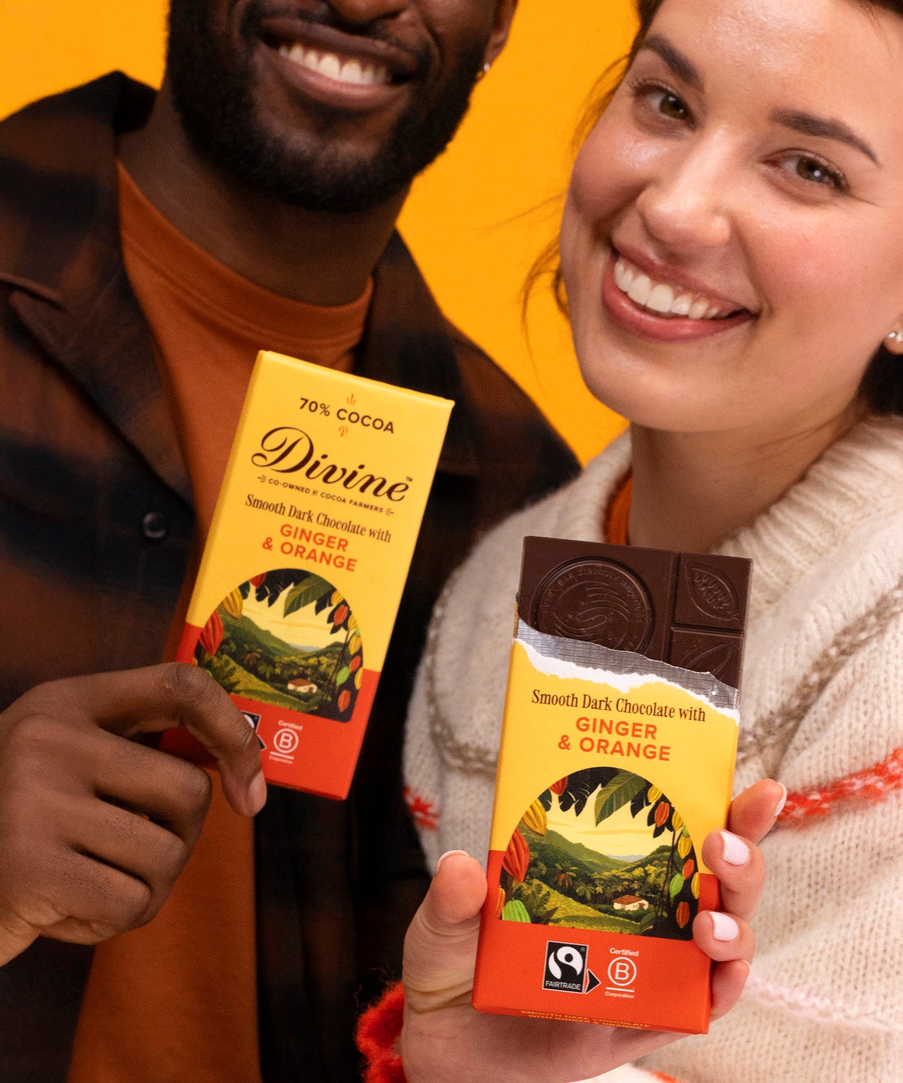 2 adults holding Divine fairtrade smooth dark chocolate with ginger and orange bars with one opened
