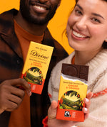 2 adults holding Divine fairtrade smooth dark chocolate with ginger and orange bars with one opened