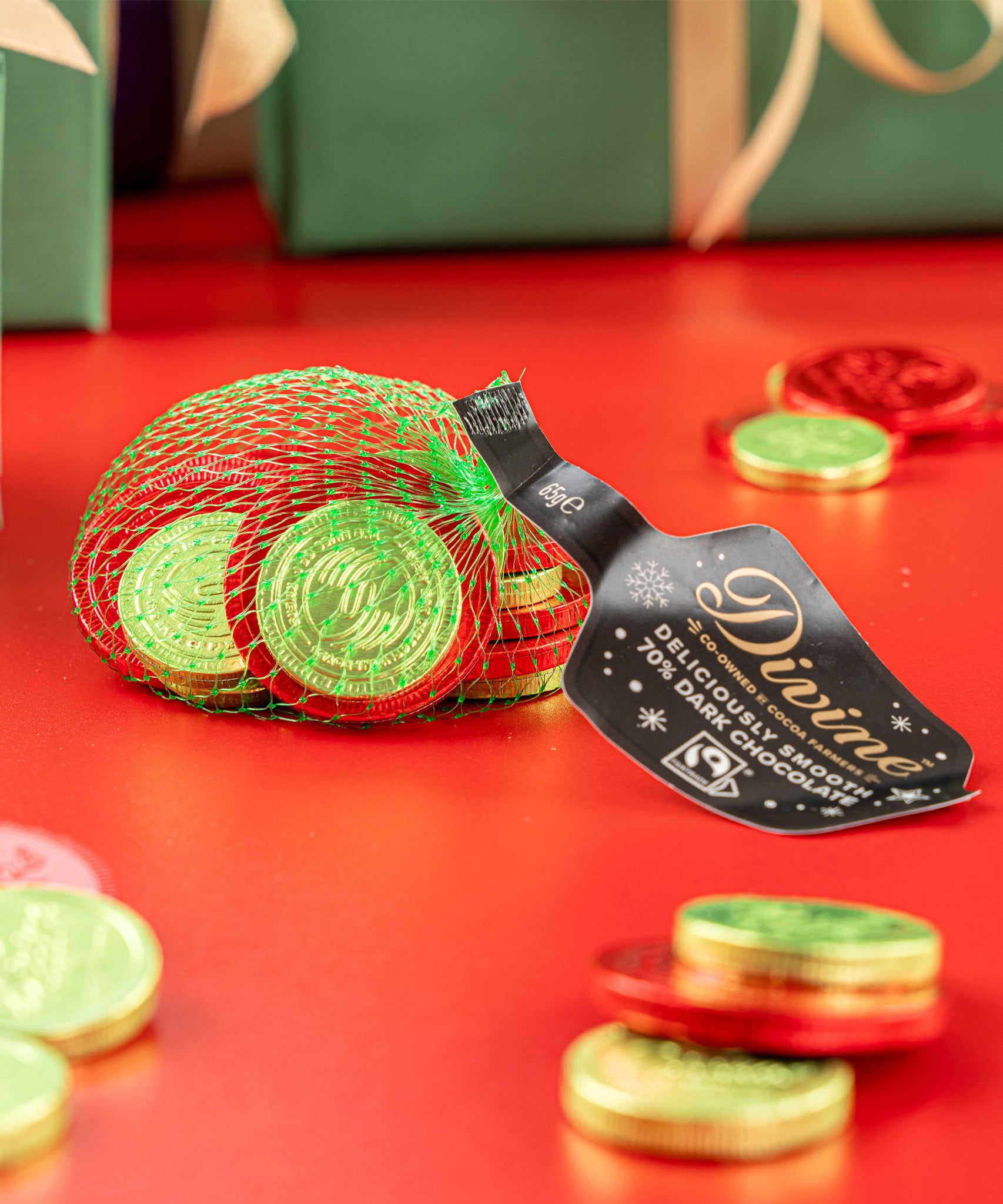Divine fairtrade dark chocolate coins inside the green netted bag with other different sized coins scatted. Chocolate coins available at Babipur.