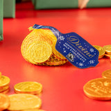 Divine fairtrade milk chocolate coins inside the yellow netted bag with other different sized coins scatted. Chocolate coins available at Babipur.